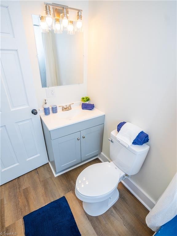 bathroom featuring wood-type flooring, toilet, and vanity