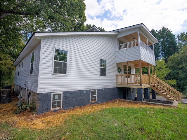 rear view of property with a balcony and a yard