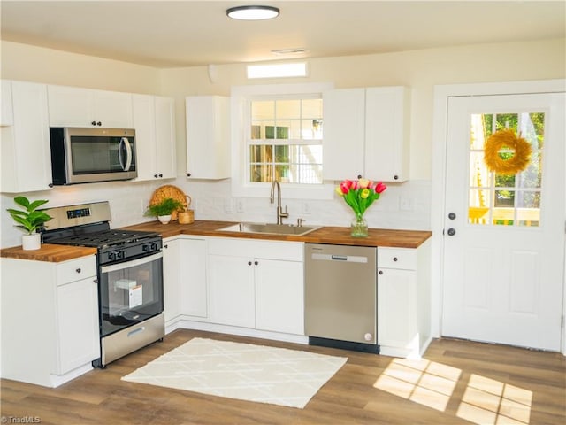 kitchen with wooden counters, appliances with stainless steel finishes, sink, and white cabinets