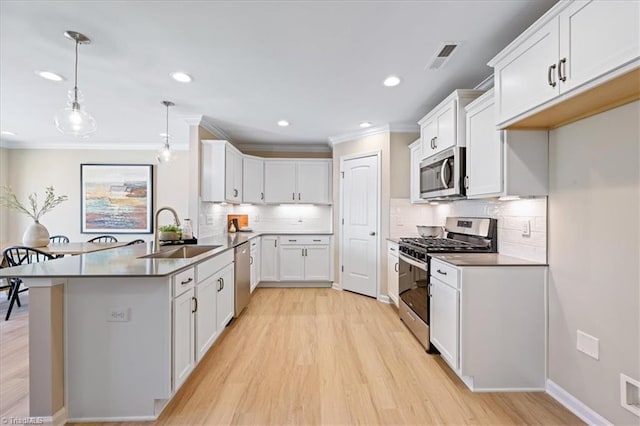 kitchen with appliances with stainless steel finishes, a sink, light wood-type flooring, a peninsula, and crown molding