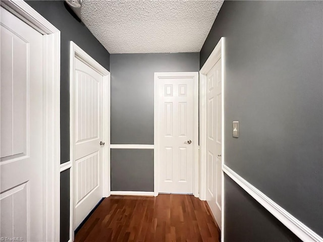 hallway with dark wood-type flooring and a textured ceiling