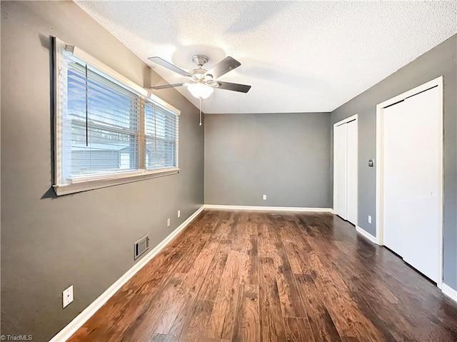 unfurnished room featuring a textured ceiling, ceiling fan, and dark hardwood / wood-style flooring