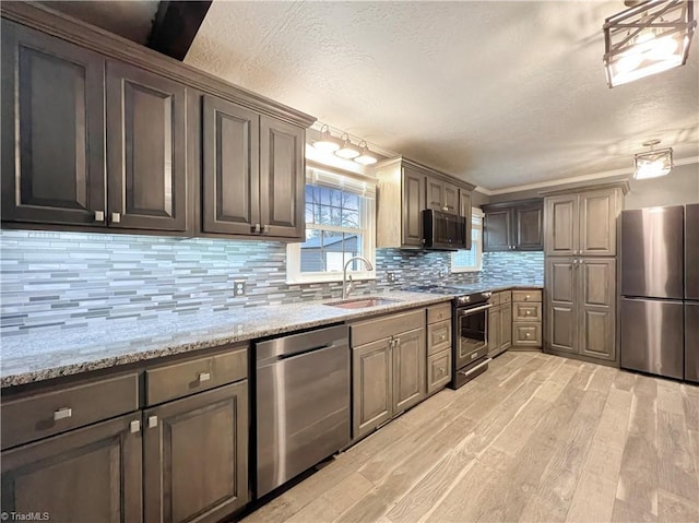 kitchen featuring light hardwood / wood-style floors, light stone countertops, tasteful backsplash, sink, and stainless steel appliances