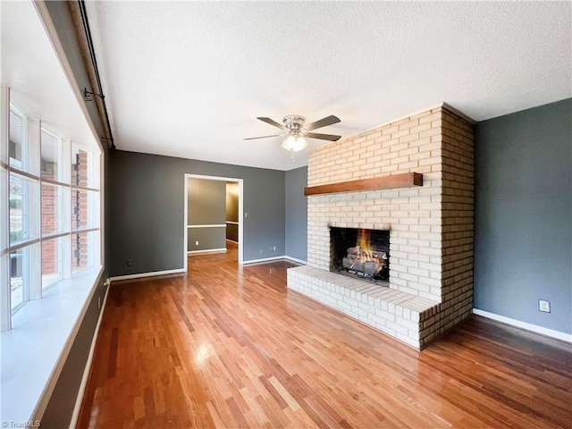 unfurnished living room with a brick fireplace, ceiling fan, a textured ceiling, and hardwood / wood-style floors