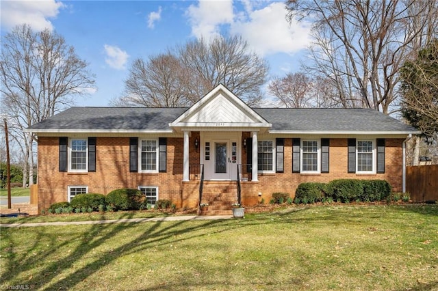 neoclassical / greek revival house with a front yard, brick siding, and fence