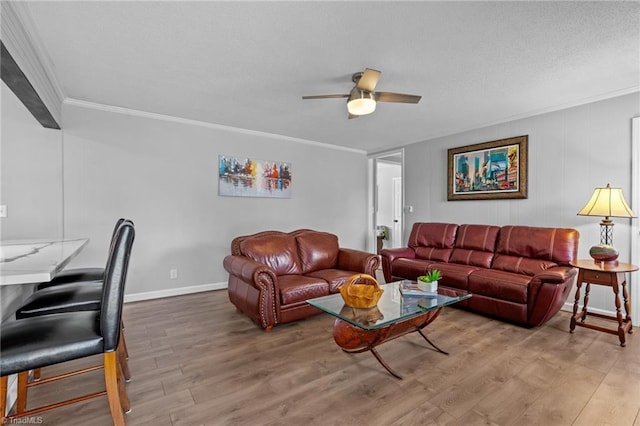 living room with baseboards, ceiling fan, ornamental molding, wood finished floors, and a textured ceiling