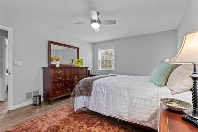 bedroom featuring ceiling fan, wood finished floors, visible vents, and baseboards