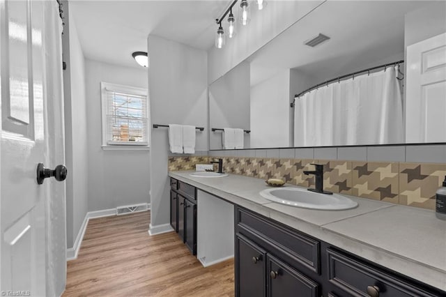 full bath with visible vents, a sink, backsplash, and wood finished floors