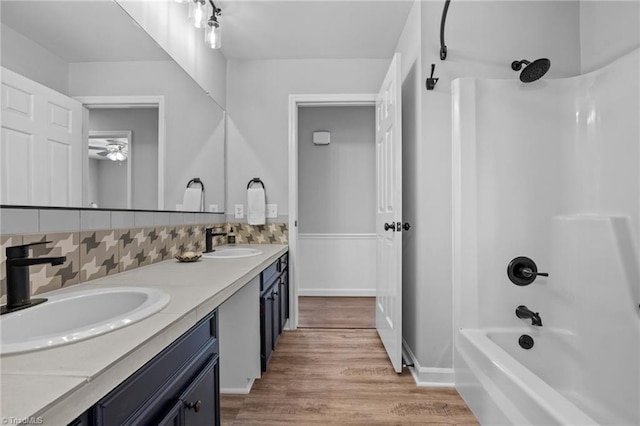 bathroom with wood finished floors, tasteful backsplash, shower / bath combination, and a sink