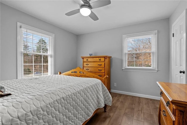 bedroom with multiple windows, ceiling fan, baseboards, and wood finished floors