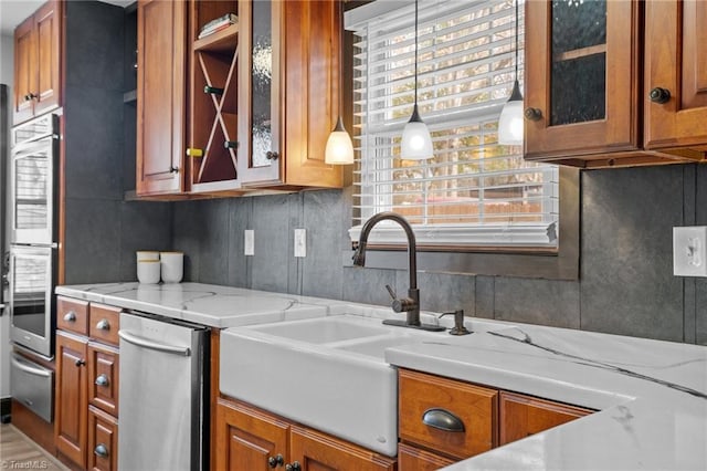 kitchen with a sink, glass insert cabinets, brown cabinetry, and a warming drawer