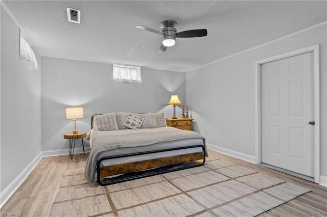 bedroom with ornamental molding, visible vents, baseboards, and wood finished floors