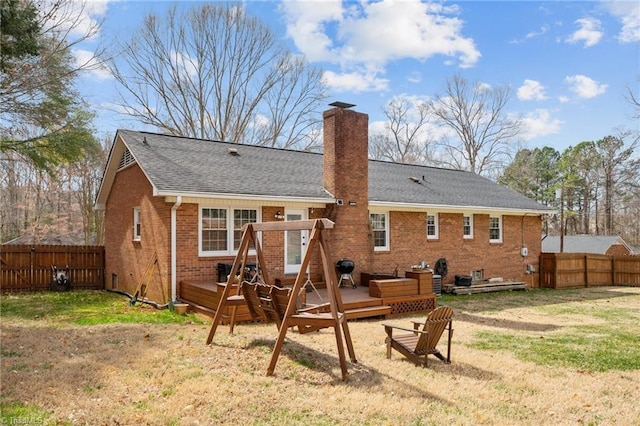 back of property with a chimney, fence, a deck, and brick siding