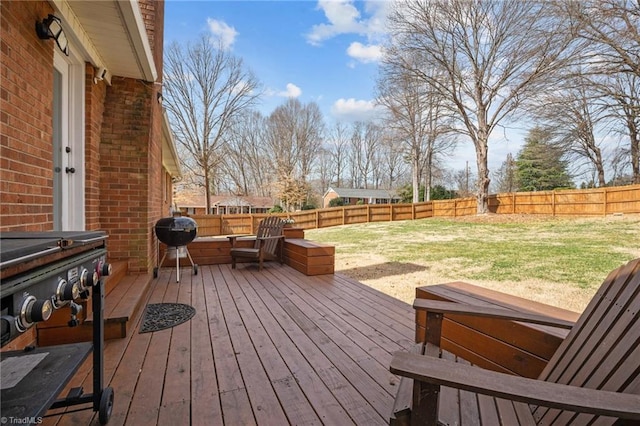 wooden terrace featuring a lawn, grilling area, and a fenced backyard