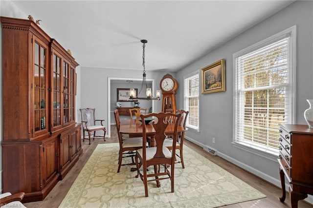 dining area with visible vents, a notable chandelier, baseboards, and wood finished floors