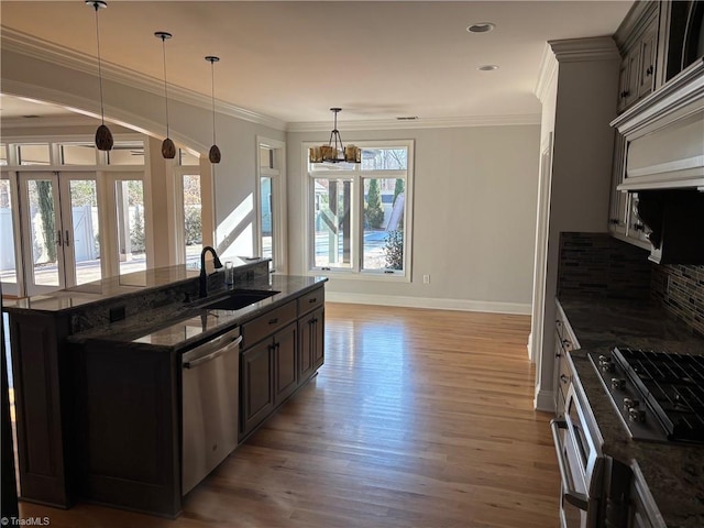 kitchen with stainless steel dishwasher, dark brown cabinetry, sink, and dark stone countertops