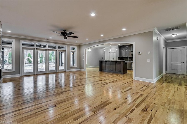 unfurnished living room featuring ceiling fan, crown molding, and light hardwood / wood-style floors