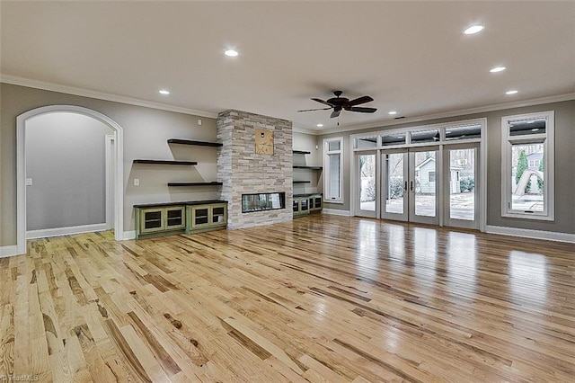 unfurnished living room with plenty of natural light, ornamental molding, ceiling fan, and light wood-type flooring