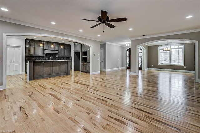 unfurnished living room with crown molding, ceiling fan with notable chandelier, and light wood-type flooring