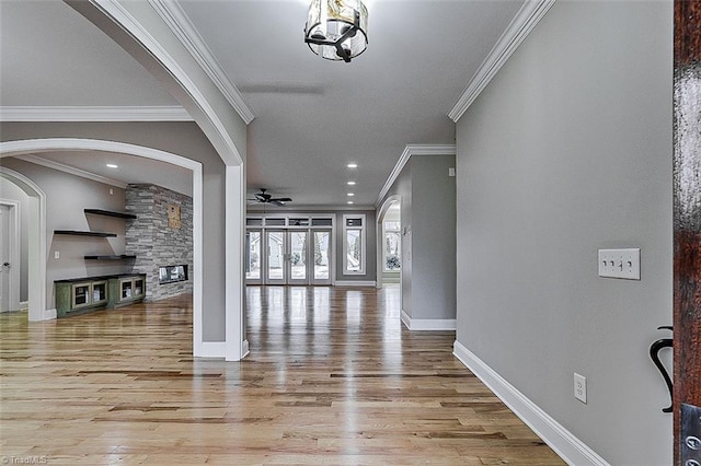 foyer with a fireplace, ornamental molding, light hardwood / wood-style floors, and ceiling fan