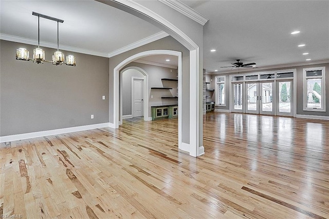 unfurnished living room featuring ornamental molding, ceiling fan with notable chandelier, and light hardwood / wood-style flooring