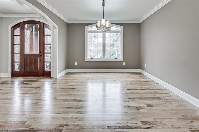 foyer entrance with ornamental molding, a notable chandelier, and light hardwood / wood-style flooring