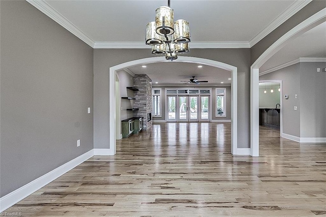 interior space featuring ceiling fan with notable chandelier, ornamental molding, and light hardwood / wood-style floors