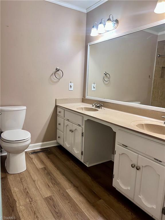 5608 Fred Lineberry Rd, Randleman, NC 27317 - full bath with ornamental molding, double vanity, toilet, and wood finished floors