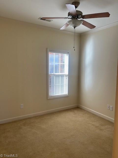 spare room featuring light carpet, baseboards, visible vents, and crown molding