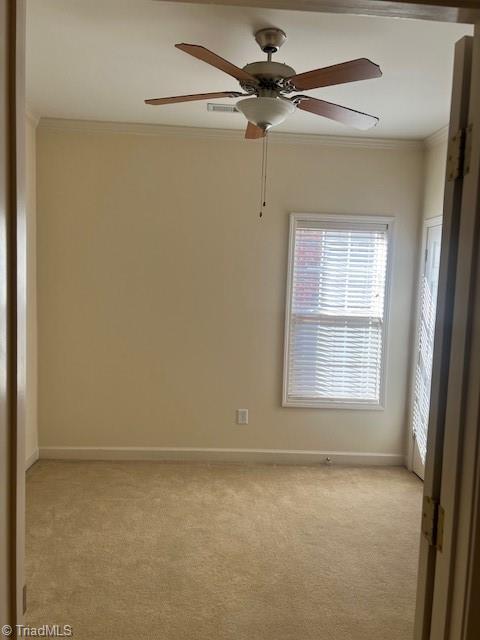 unfurnished room featuring a ceiling fan, baseboards, crown molding, and light colored carpet