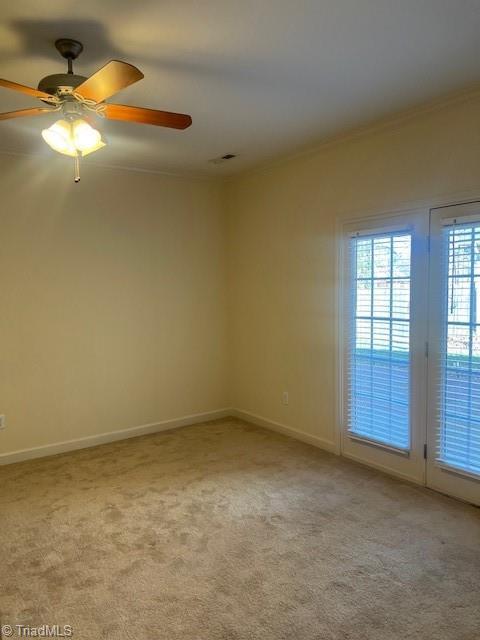 unfurnished room featuring light carpet, baseboards, visible vents, and crown molding