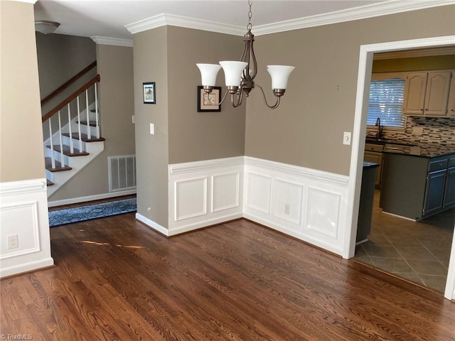 3908 Sandlewood Rd, High Point, NC 27265 - unfurnished dining area featuring dark wood finished floors, ornamental molding, a chandelier, and stairs