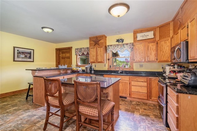 kitchen featuring a kitchen bar, appliances with stainless steel finishes, a kitchen island, and sink