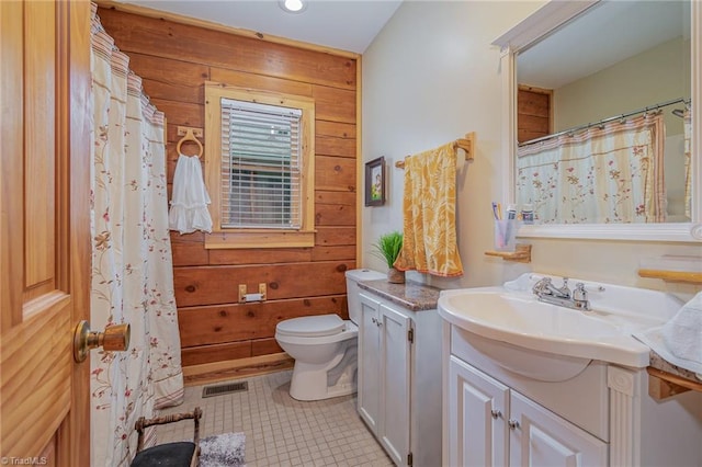 bathroom with tile patterned floors, wooden walls, vanity, and toilet