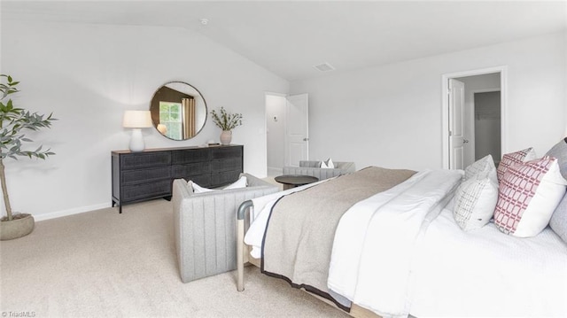 bedroom with light colored carpet, a closet, a walk in closet, and vaulted ceiling