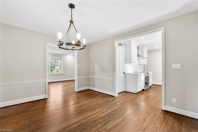 unfurnished dining area with wood-type flooring and a notable chandelier