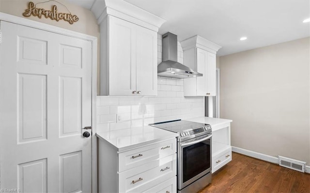 kitchen with backsplash, wall chimney range hood, dark hardwood / wood-style floors, white cabinetry, and stainless steel electric range