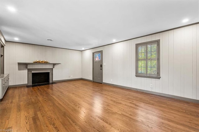 unfurnished living room featuring light hardwood / wood-style floors and a brick fireplace