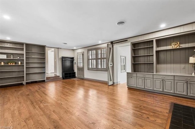 unfurnished living room featuring a barn door and light hardwood / wood-style flooring