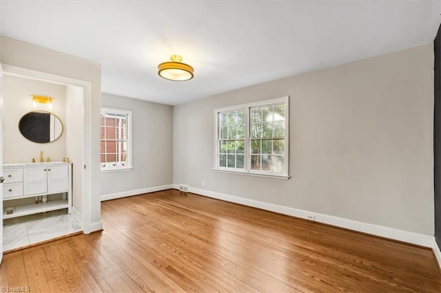 unfurnished bedroom featuring ensuite bathroom, sink, and wood-type flooring