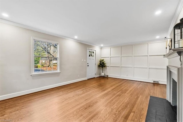 unfurnished living room featuring ornamental molding and light hardwood / wood-style flooring