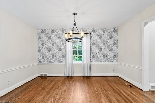 unfurnished dining area with hardwood / wood-style floors and a notable chandelier