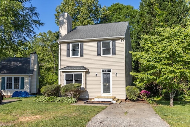 colonial-style house with a chimney and a front yard