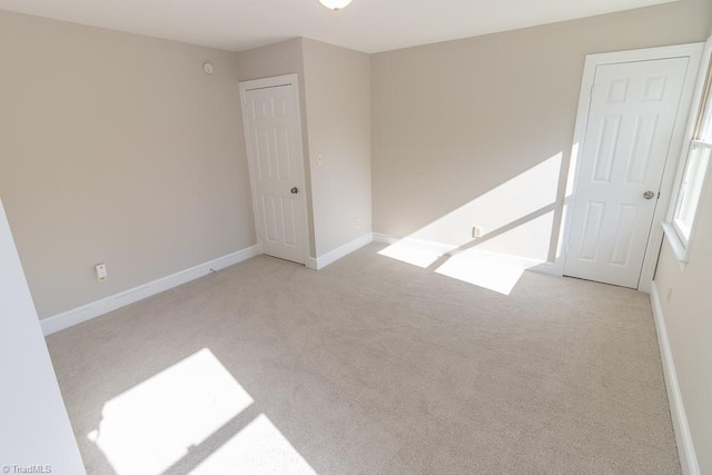 empty room featuring baseboards and light carpet
