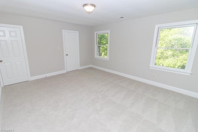 empty room with plenty of natural light, baseboards, and light carpet