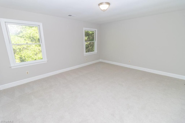 spare room with baseboards, visible vents, light carpet, and a wealth of natural light