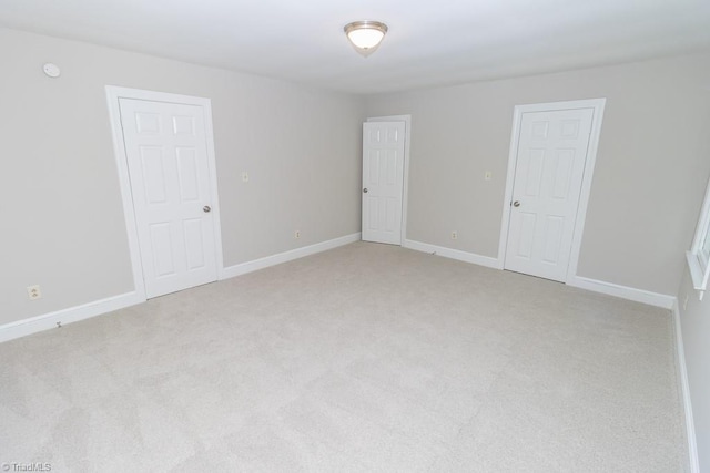 empty room featuring light colored carpet and baseboards