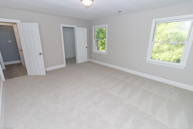 unfurnished bedroom featuring baseboards, visible vents, and light carpet
