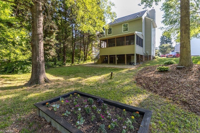 back of house featuring a yard, a chimney, and a sunroom