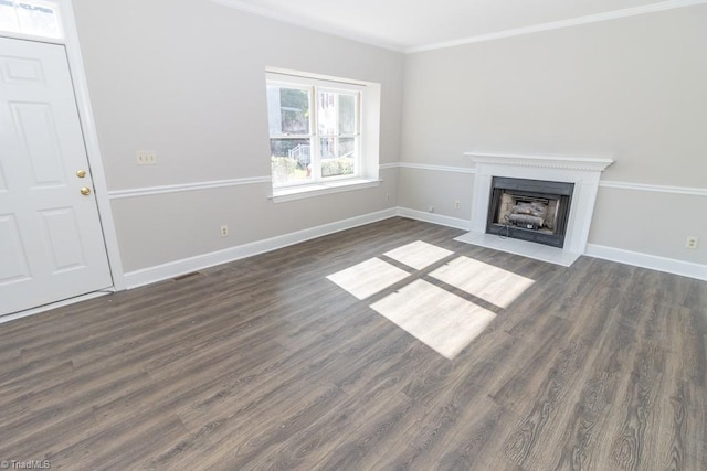 unfurnished living room featuring crown molding, baseboards, dark wood-style flooring, and a fireplace with flush hearth